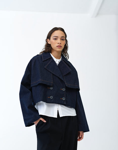 Woman wearing a cropped denim trench coat over a white shirt