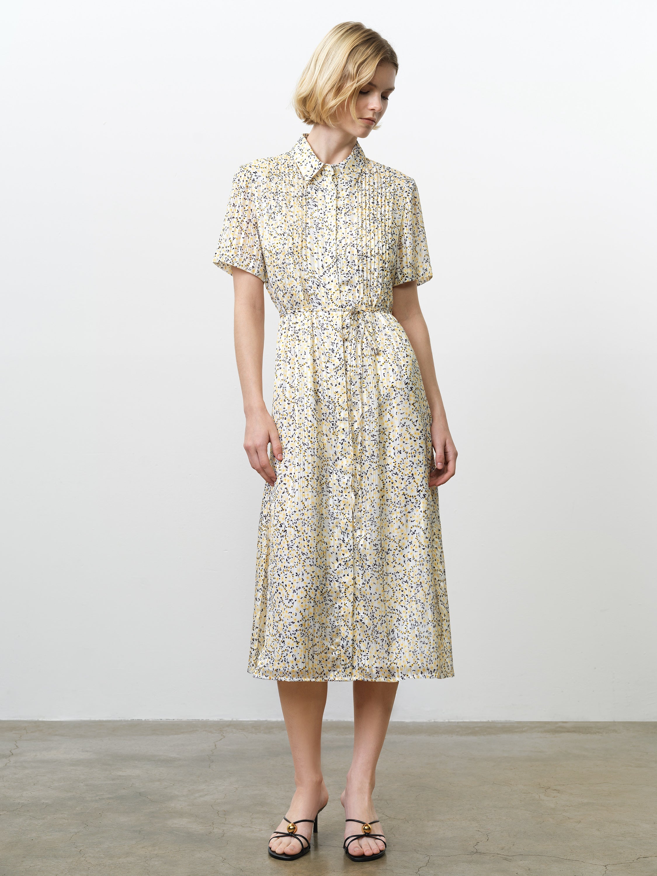 Woman wearing a floral midi length shirt dress, with short sleeves, a collar and a tie waist