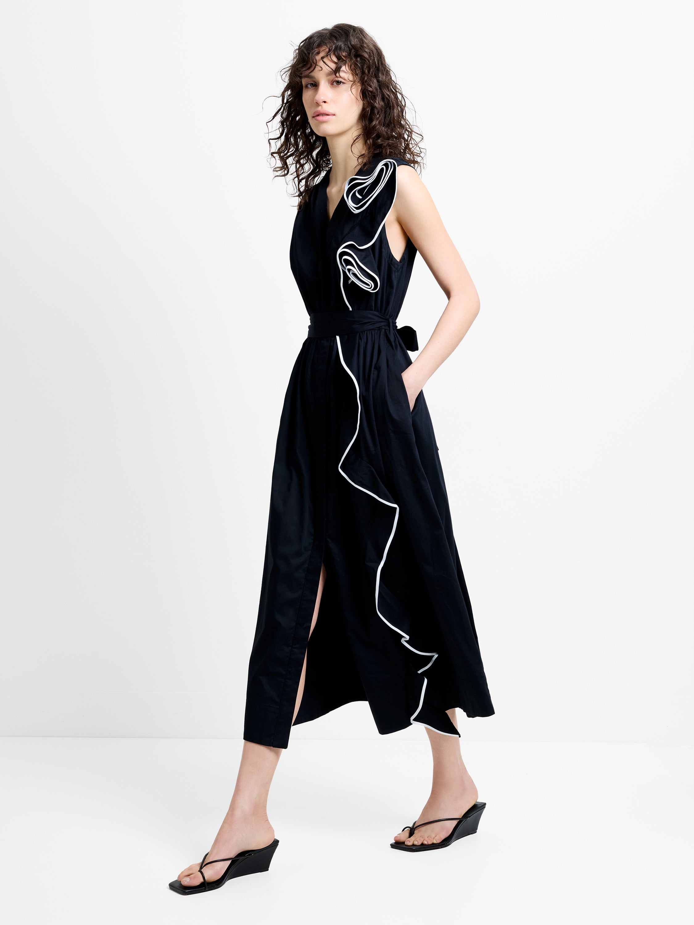 Woman wearing a sleeveless black and white dress, with corsage piping detailing and a V neckline