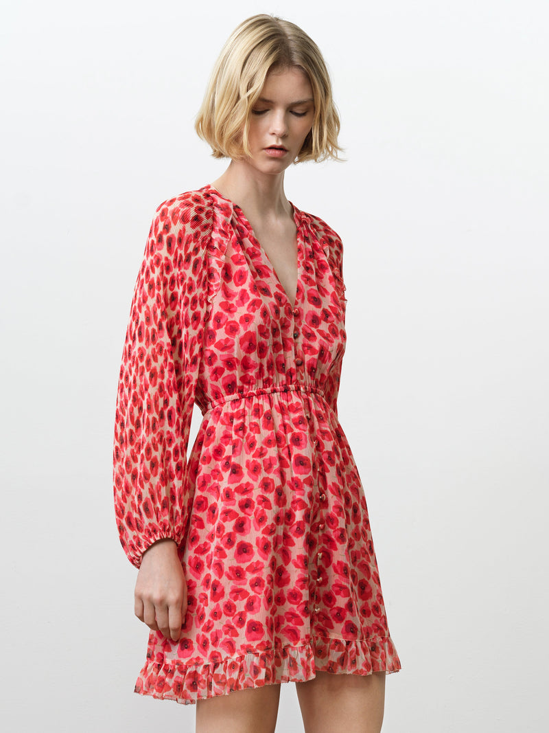 Woman wearing a long sleeve chiffon mini dress with a V neckline and a gathered waist in a bright poppy floral print