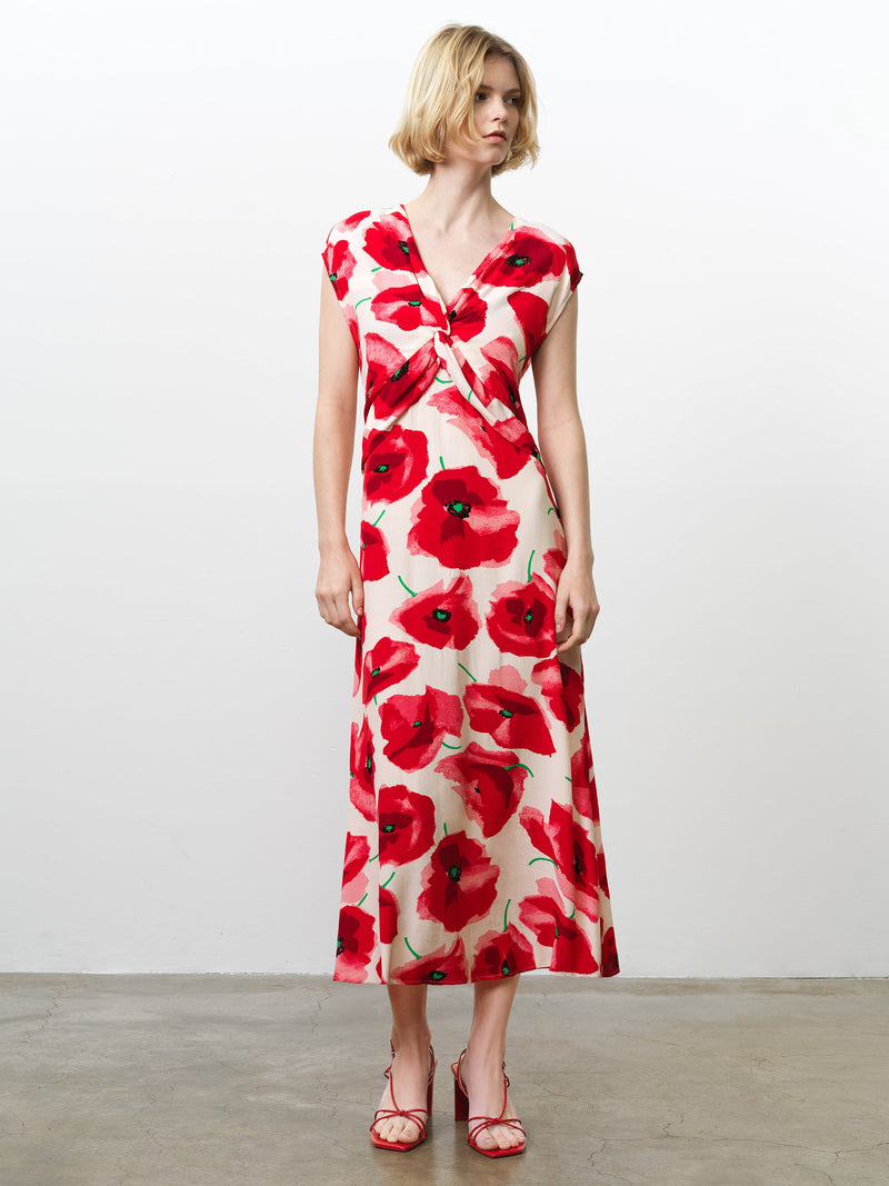 Woman wearing a floral poppy print midi dress, with cap sleeves, a V neckline and a twist knot front detail