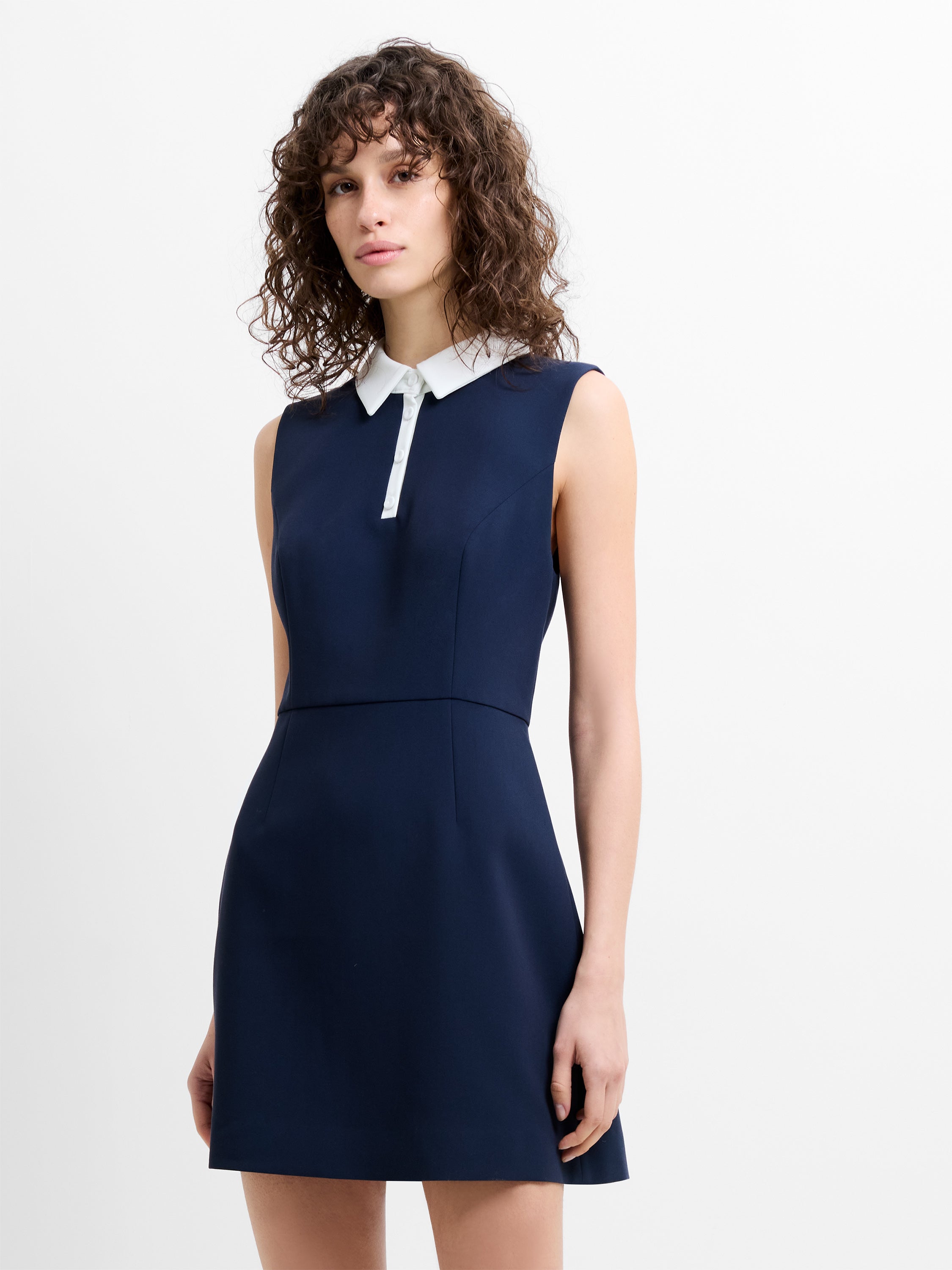 Woman wearing a navy blue mini  dress with a white collar 