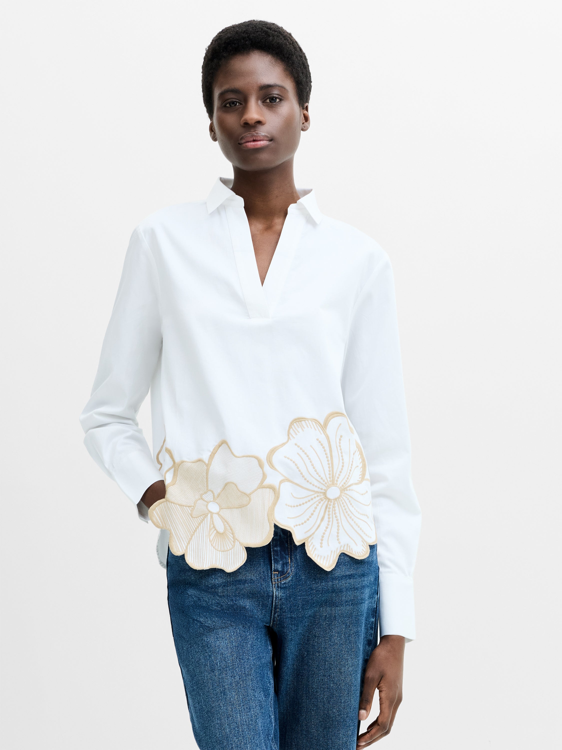 Woman wearing a cotton relaxed fit floral embroidered shirt with long sleeves and an open v neck collar.