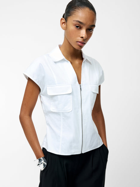 A woman wearing a white v-neck zip through top with 2 front pockets and short sleeves.