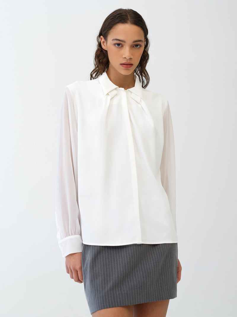 Woman wearing a white long sleeve blouse and a grey skirt 