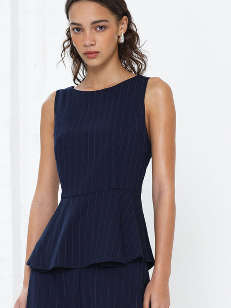 Woman wearing a sleeveless navy pinstripe peplum top 