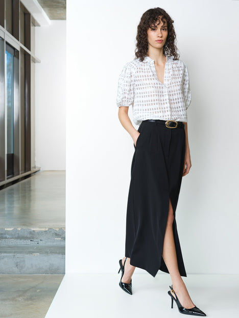 Woman wearing a semi sheer black and white check blouse with short sleeves and a V neckline