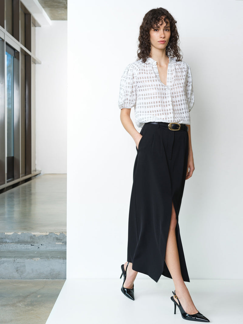Woman wearing a semi sheer black and white check blouse with short sleeves and a V neckline