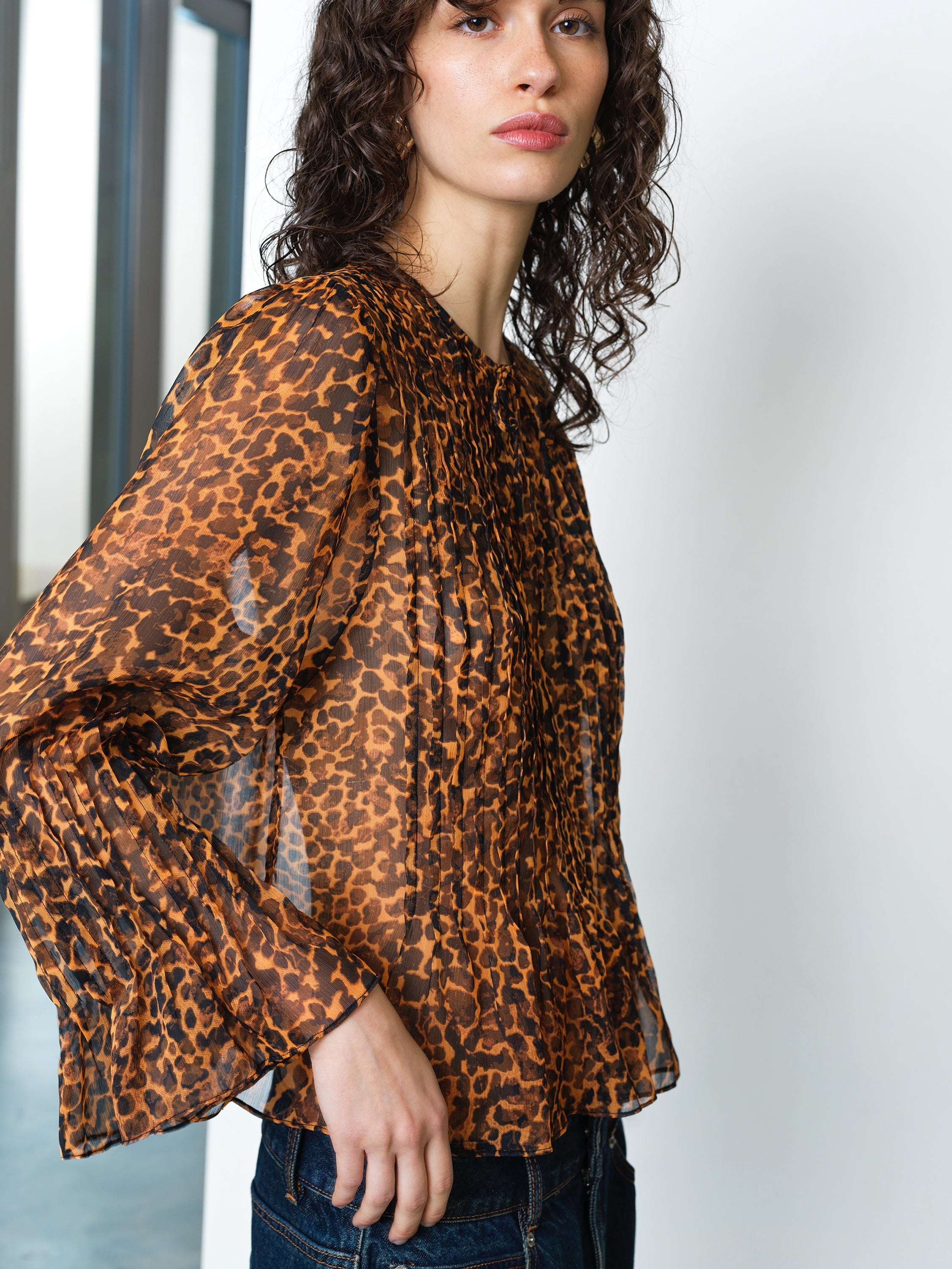 Woman wearing a long sleeve leopard print chiffon blouse with a peplum hem