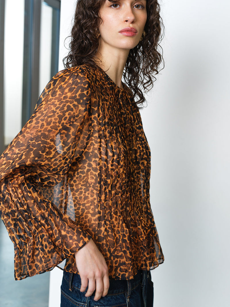 Woman wearing a long sleeve leopard print chiffon blouse with a peplum hem