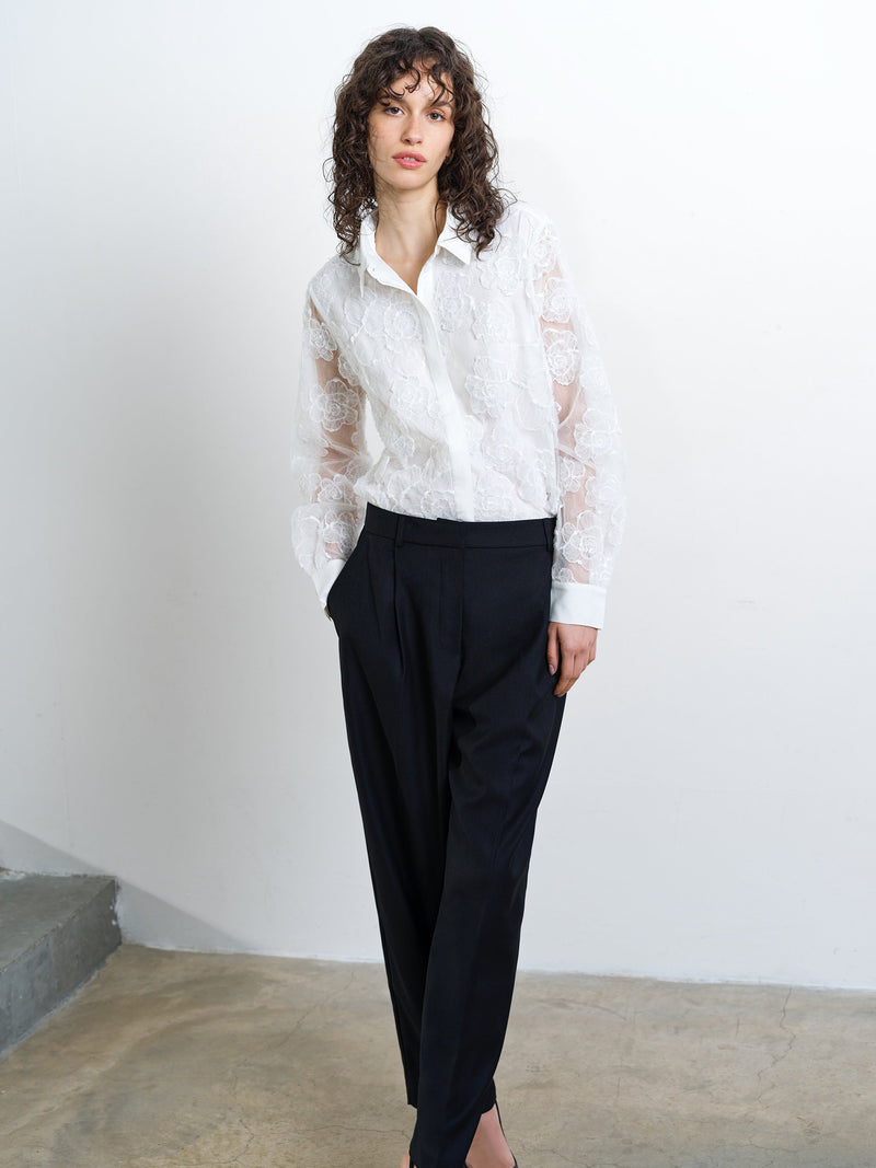 Woman wearing a white floral lace shirt with sheer long sleeves
