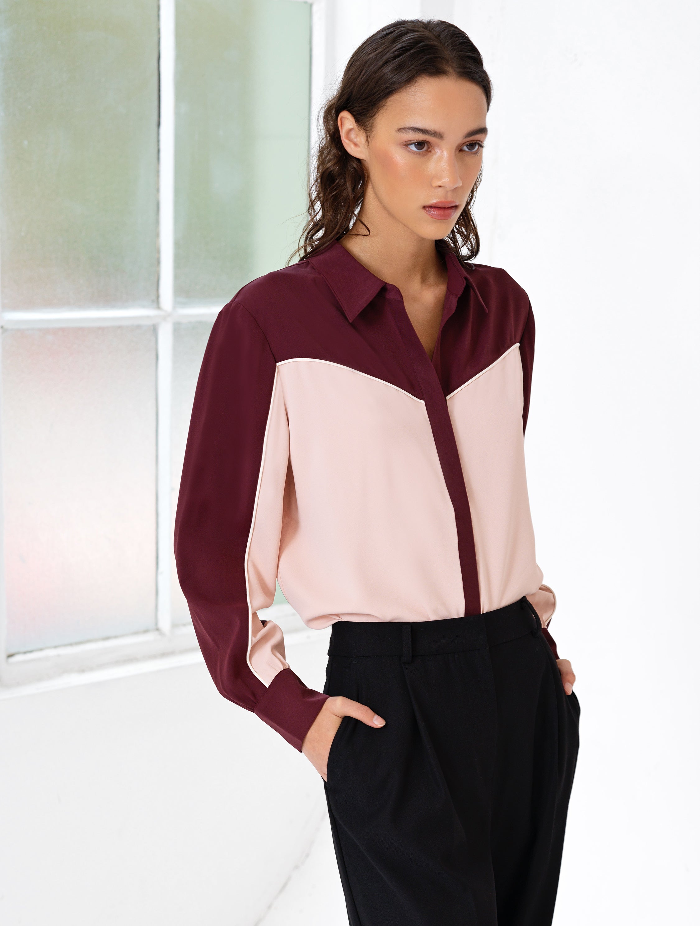 Woman wearing a burgundy and light pink long sleeve shirt