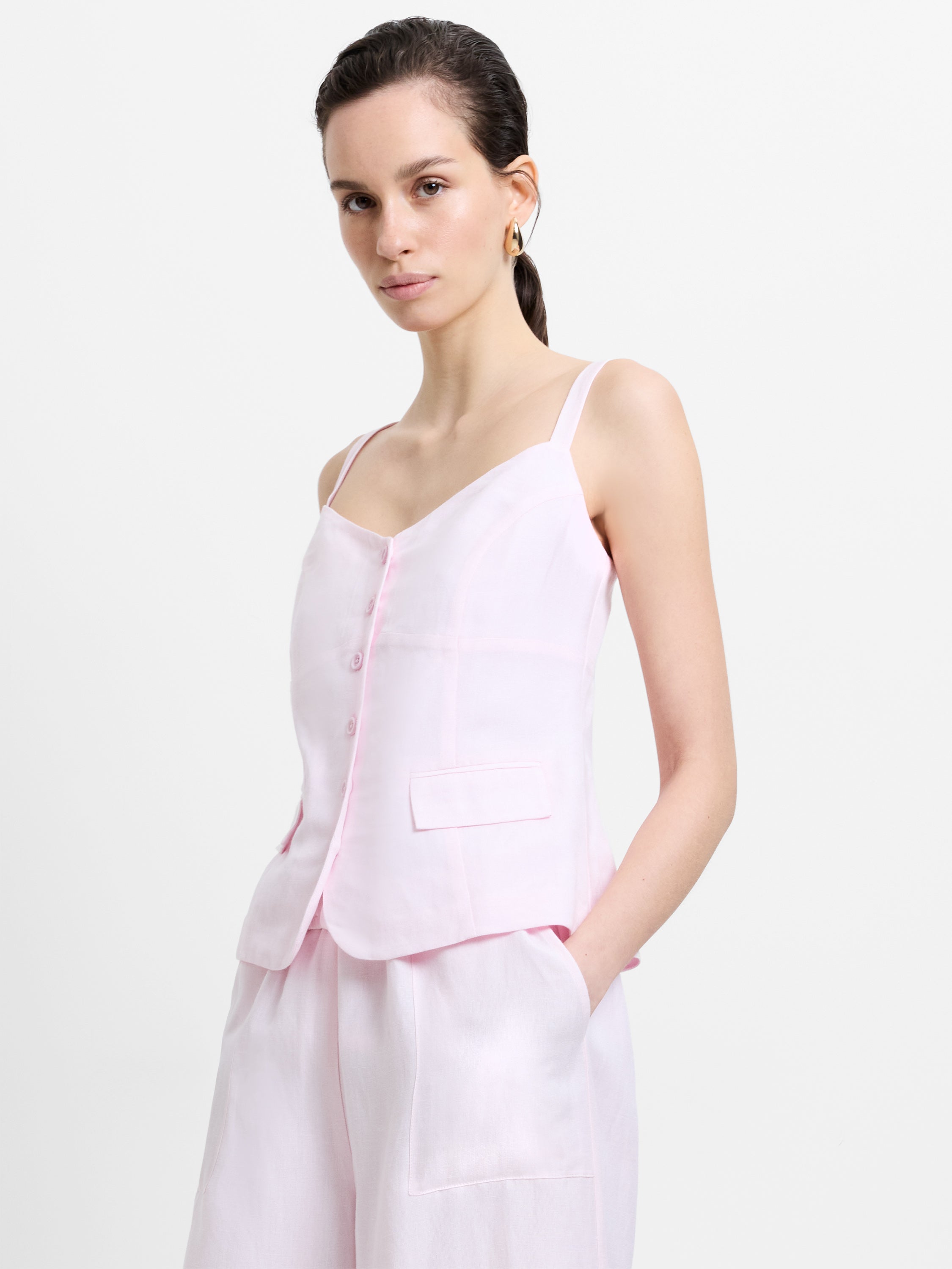 Woman wearing a strappy pink linen top with a sweetheart neckline and button down detailing