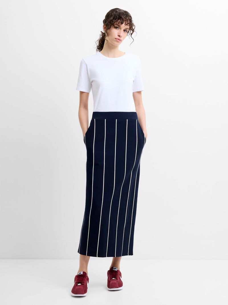 Woman wearing a white t-shirt and a navy pinstripe midi skirt with pockets