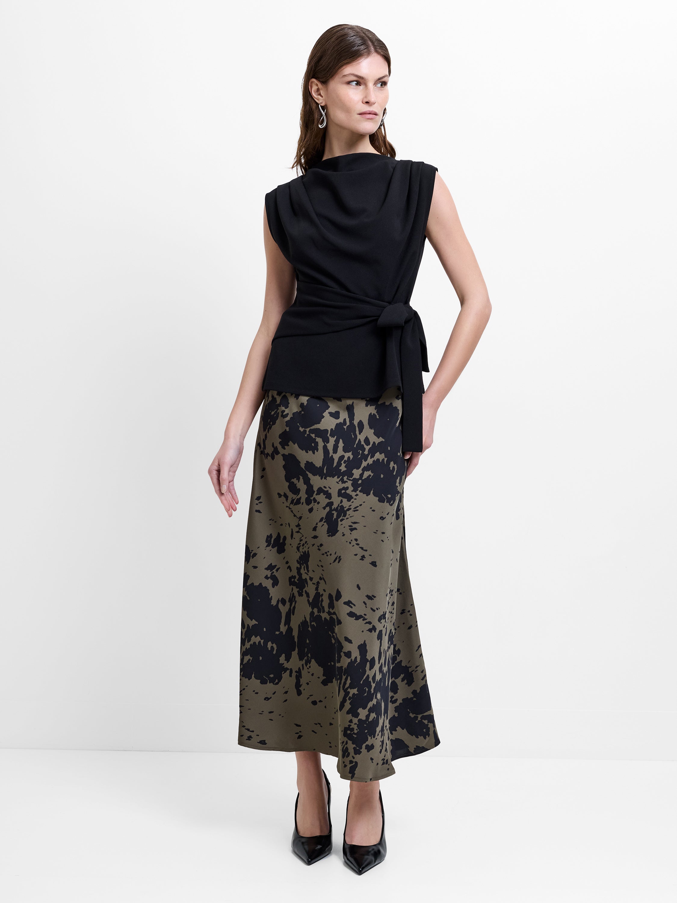 Woman wearing a green and black abstract printed midi skirt, with a high waisted elasticated waistband
