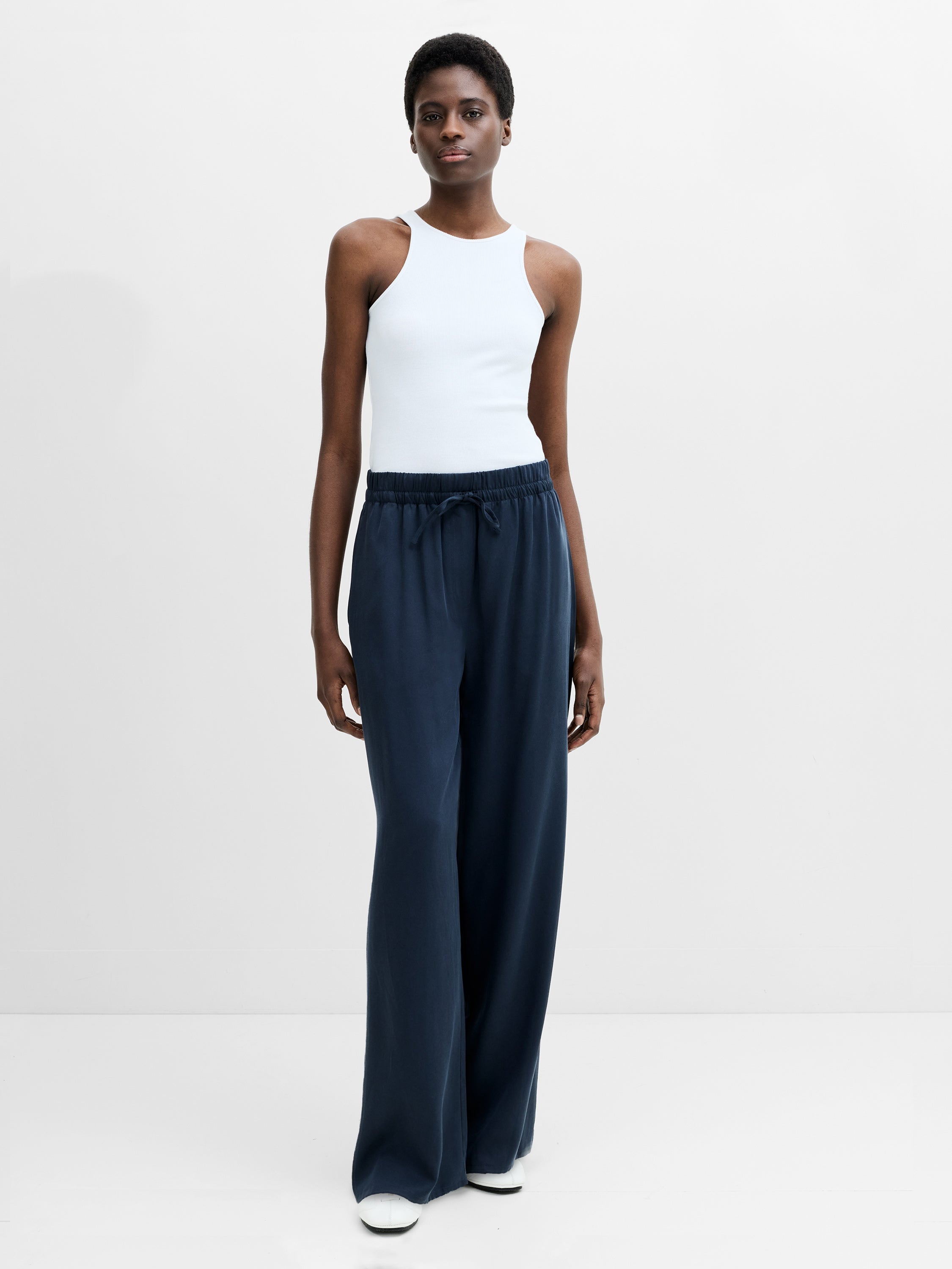 A woman wearing navy full length wide fit trousers with an adjustable waist 