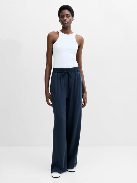 A woman wearing navy full length wide fit trousers with an adjustable waist 