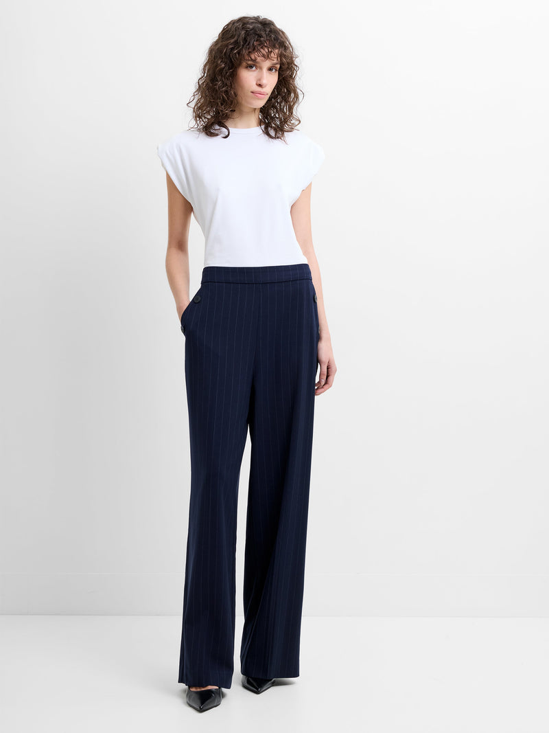 Woman wearing a white top and navy pinstripe wide leg trousers