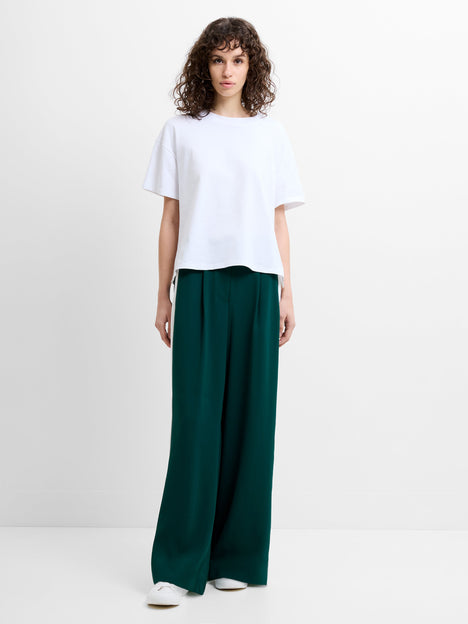 Woman wearing a white T-shirt and dark green wide-leg trousers with a white side stripe