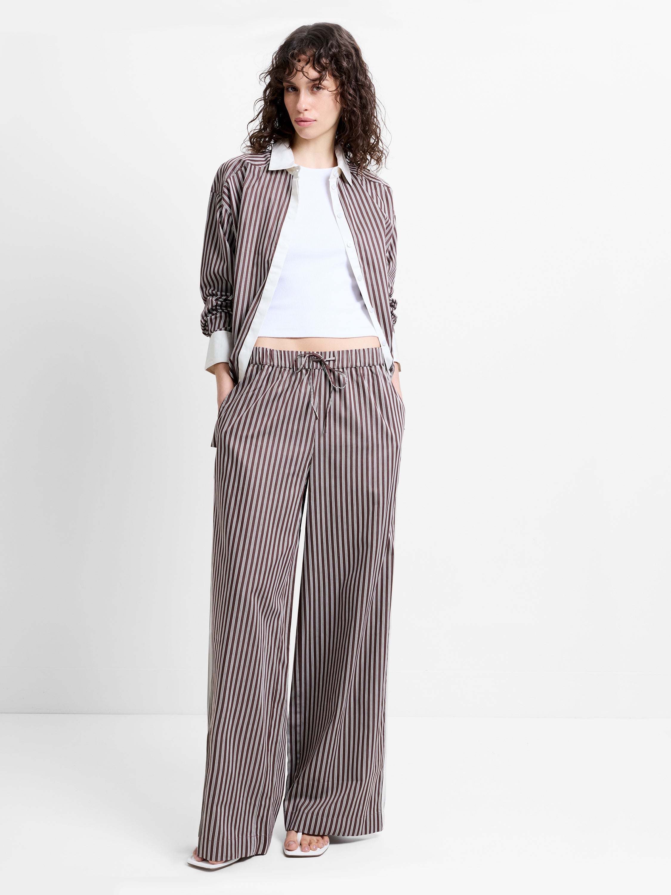 Woman wearing high waisted, wide leg brown and white striped trousers