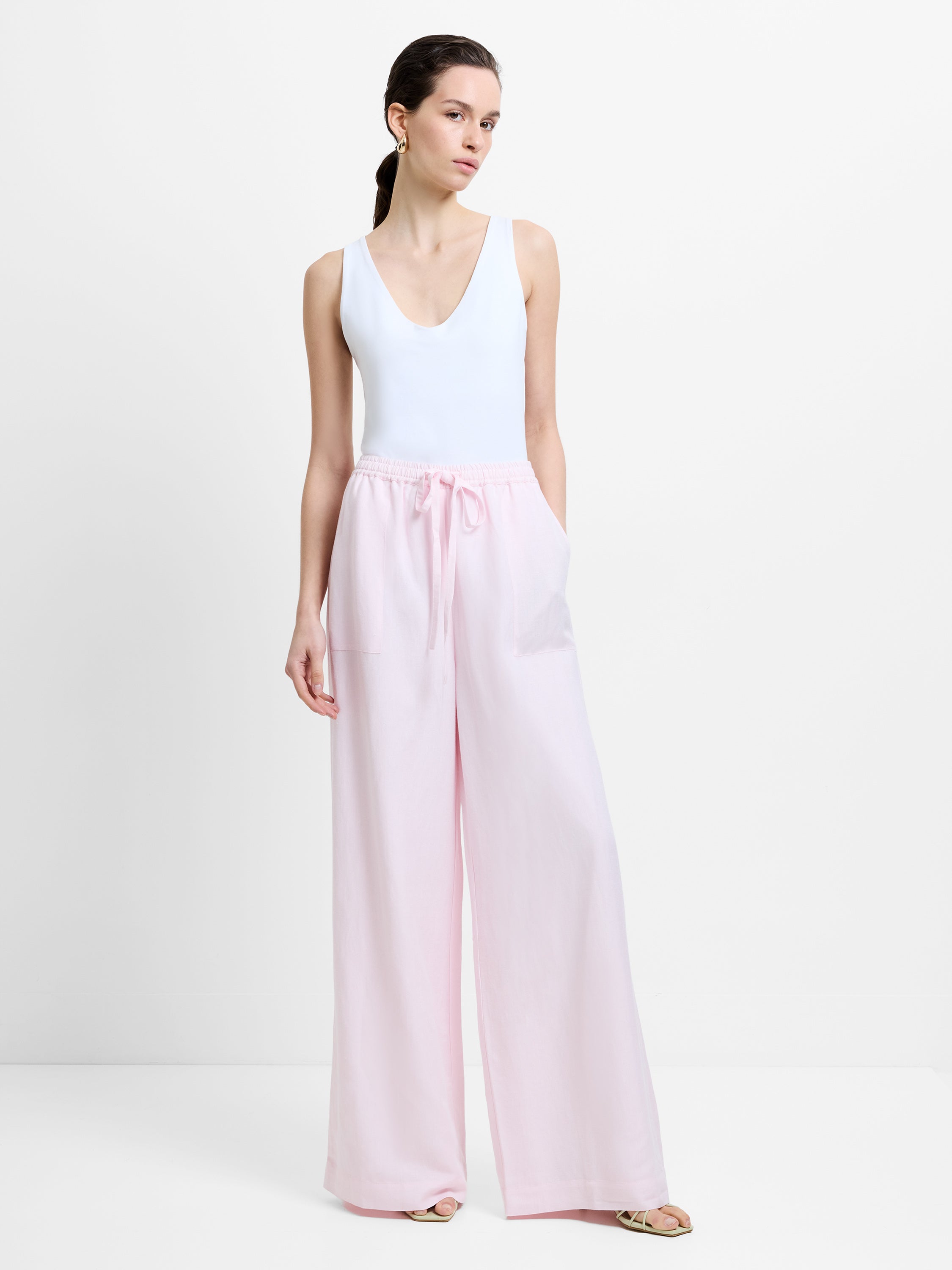 Woman wearing high waisted, drawstring waist wide leg white linen trousers