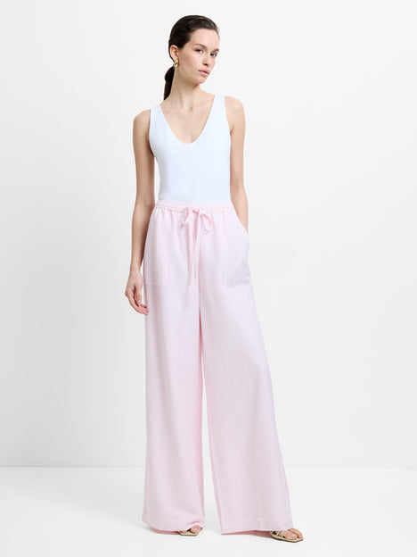 Woman wearing high waisted, drawstring waist wide leg white linen trousers