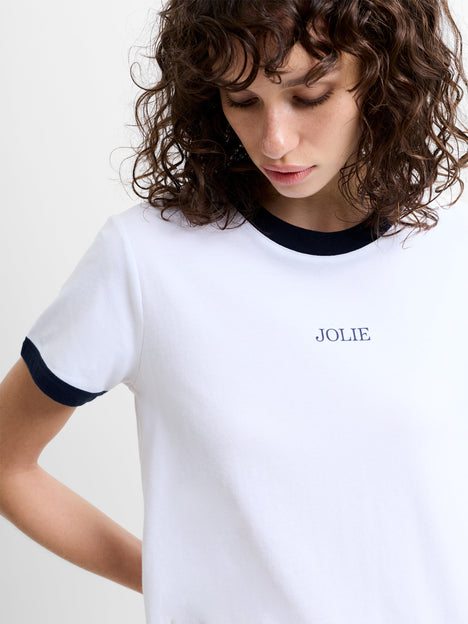 Person wearing a white short sleeve T-shirt with 'JOLIE' graphic