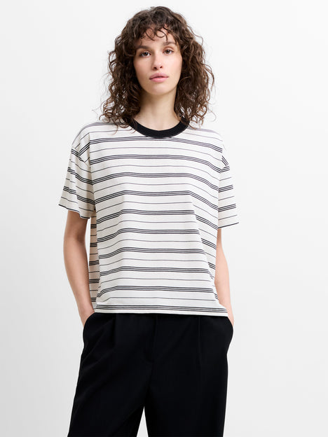 Woman wearing a short sleeve relaxed fit T-shirt, with cream and black horizontal stripes and a ringer neckline