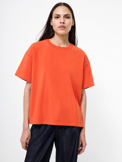 Woman wearing an oversized orange t-shirt and dark trousers