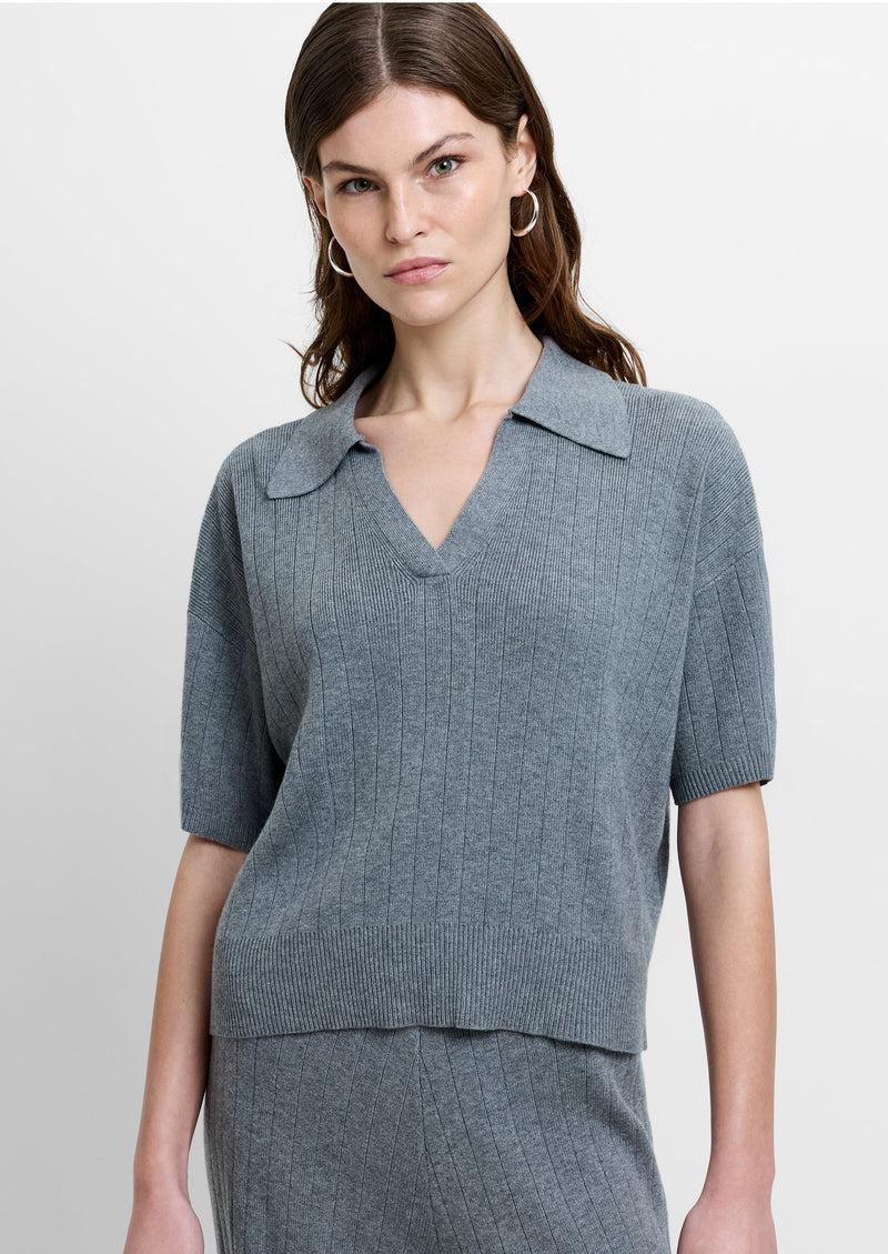 Woman wearing a grey, short sleeve knitted polo top with a collared V neckline
