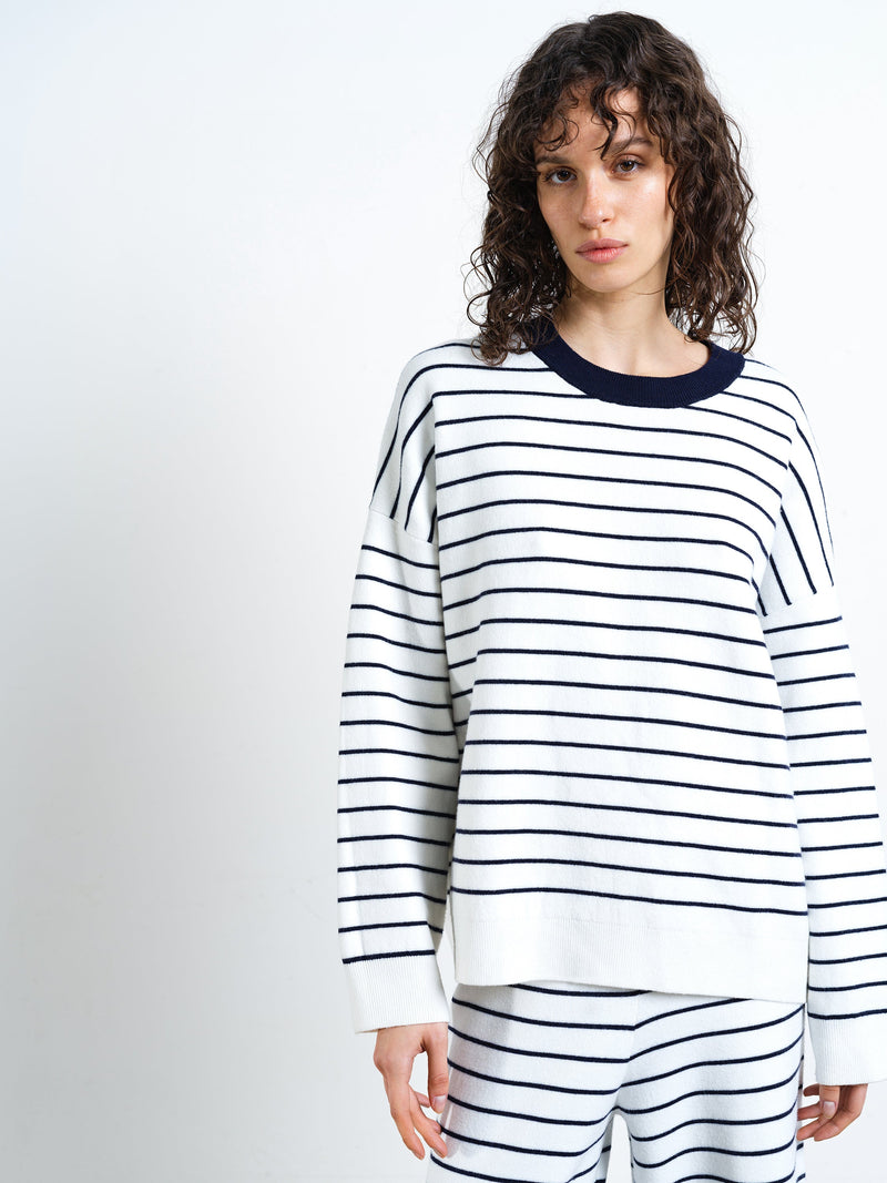 Woman wearing a white and navy striped crew neck knitted jumper with matching wide leg trousers