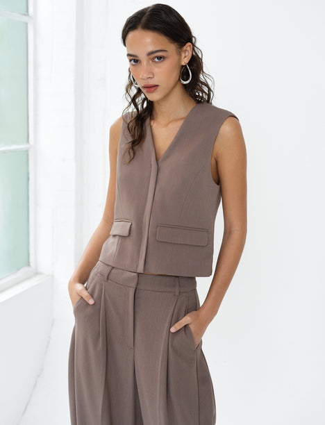Woman wearing a taupe brown sleeveless V-neck waistcoat with matching barrel leg trousers