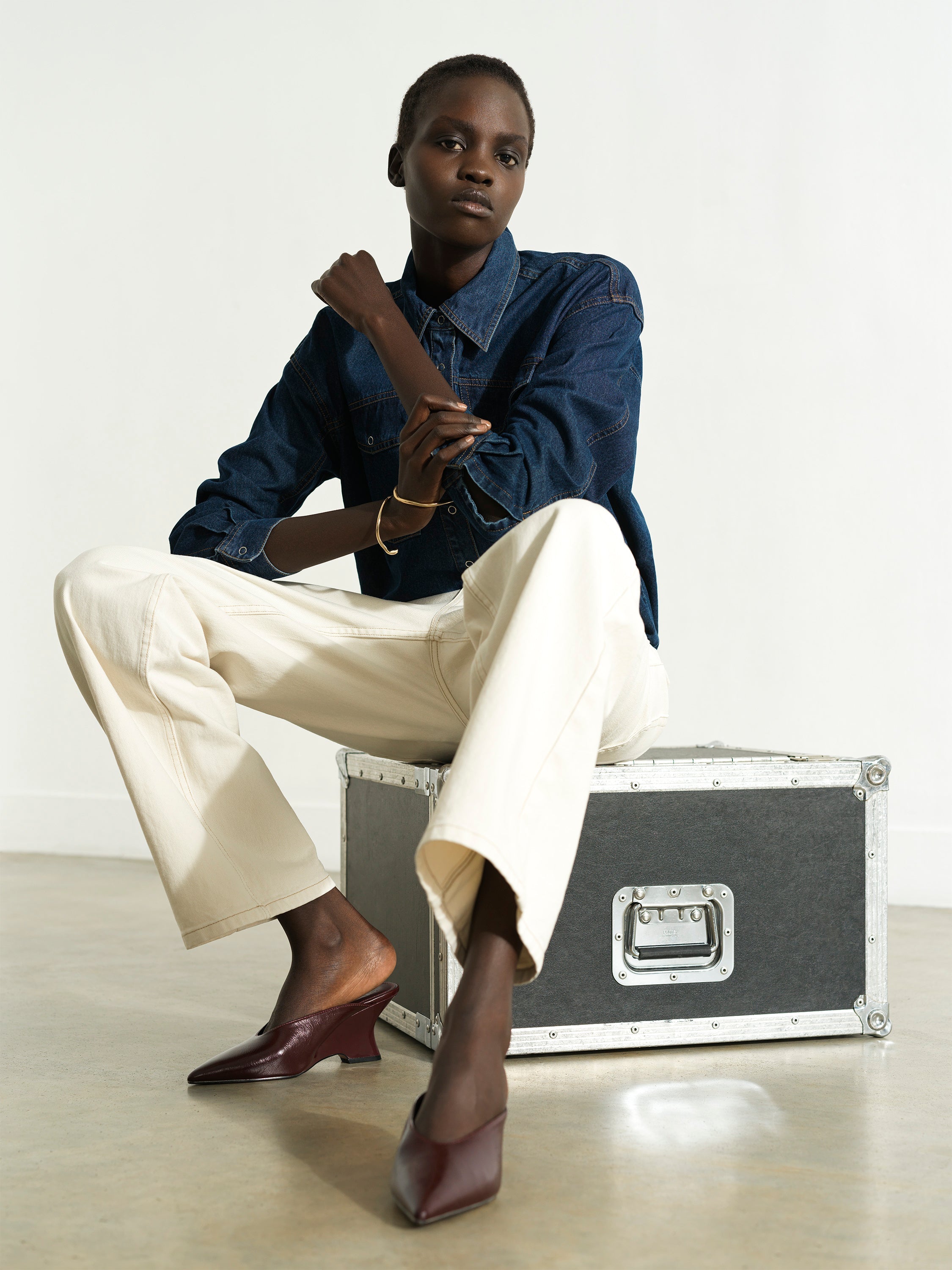 Woman wearing a long sleeve blue denim shirt with cream wide leg jeans