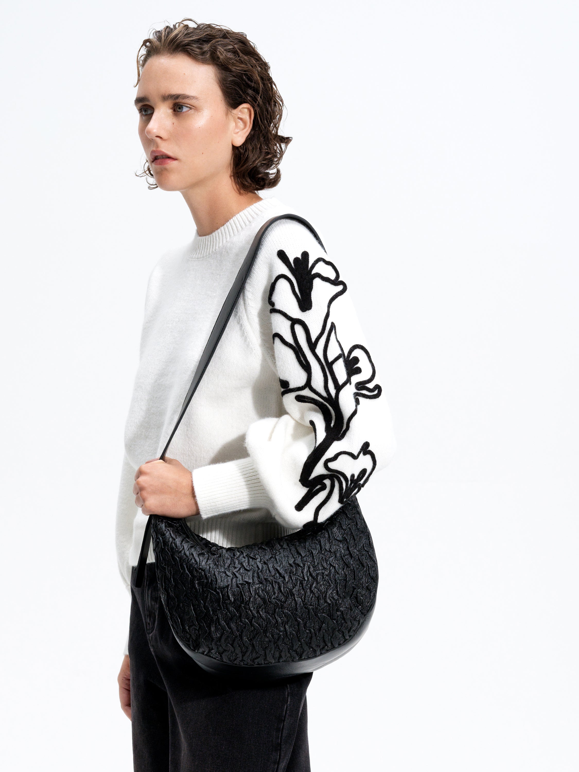 Woman wearing a white knitted jumper with black floral embroidered balloon sleeves